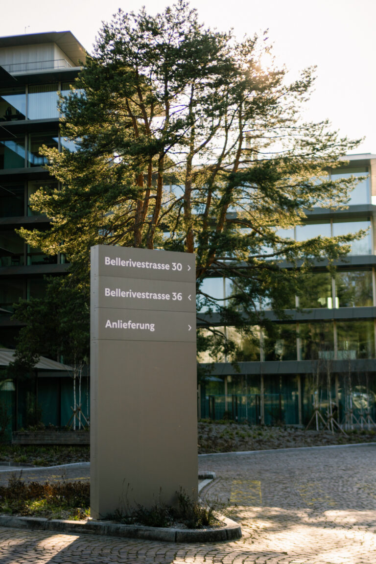 Dunkle Orientierungsstele mit Adressangaben Bellerivestrasse vor einem Gewerbeareal