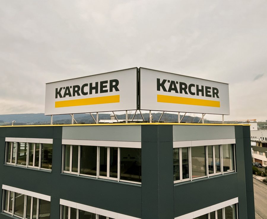 Grosse Leuchtkästen mit Kärcher Logo an Dach und Fassadenecke eines Gewerbegebäudes